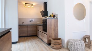 Ett modernt kök med träskåp, en inbyggd ugn och en liten matplats med en rund spegel och pallar.