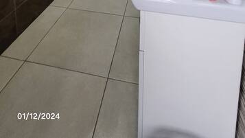 A modern bathroom with a white sink, a mirror, and a shower area.