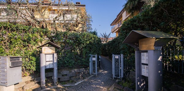 A gated entrance with a cobblestone path leading to a building. - Villaggio dei Fiori - App Primula (Sirmione)