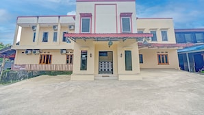 A two-story building with a flat roof, a central entrance with a decorative gate, and multiple windows. - Hotel O Puncak Bogor Near Taman Safari Formerly Hotel Satya Luhur (Megamendung)