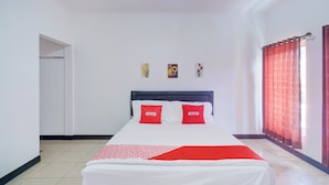 A neatly made bed with white and red bedding, two pillows with "OYO" text, a red curtain, and a small painting on the wall. - Hotel O Puncak Bogor Near Taman Safari Formerly Hotel Satya Luhur (Megamendung)
