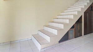A staircase with a beige wall and a tiled floor. - Hotel O Puncak Bogor Near Taman Safari Formerly Hotel Satya Luhur (Megamendung)