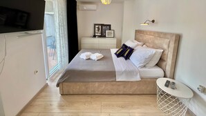 A modern bedroom with a bed, bedside table, and a hanging light fixture. - Apartman Jasmin 1 (Crikvenica)