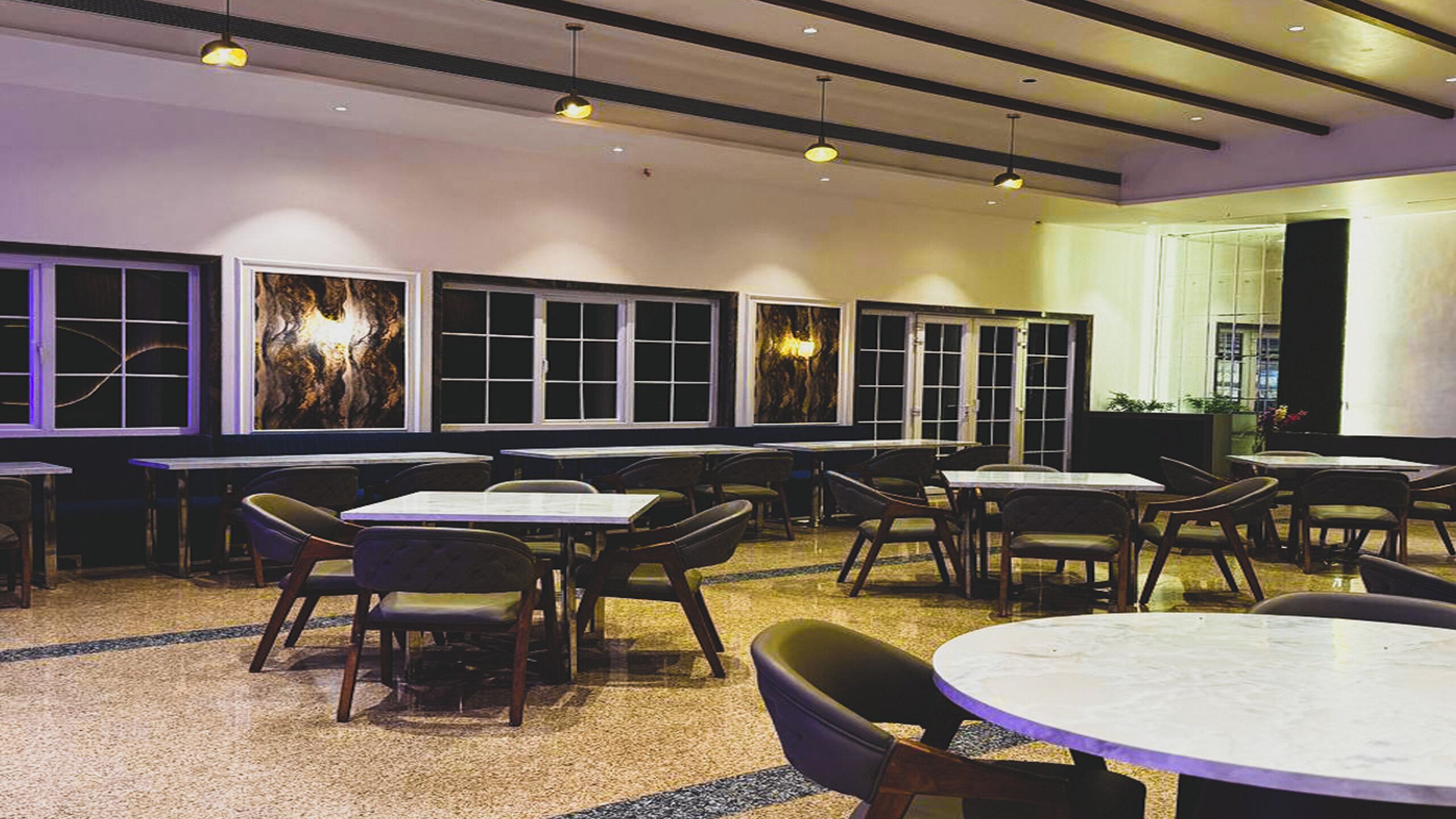 A restaurant with multiple tables and booths, featuring a modern interior with a mix of natural and artificial lighting.