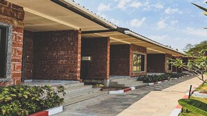 A row of brick buildings with covered walkways and steps leading to the entrance. - Discover Resorts Pali (Sudhagad)