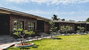 A modern building with a flat roof, large windows, and a well-maintained lawn with several small trees.