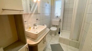 Une salle de bain avec un lavabo, des toilettes et une douche.
