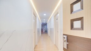 A modern hotel corridor with wooden paneling, marble flooring, and recessed lighting. - Hotel O Tanjung Duren Near Mall Citraland Formerly Suba Hotel (Jakarta)