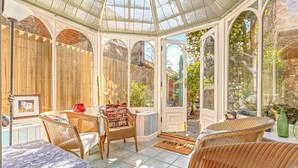 A conservatory with wicker furniture, a glass door leading outside, and a framed picture on the wall. - Basketmakers Cottage (Henley-On-Thames)