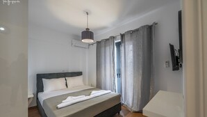 Una cama bien hecha con cabecera, una mesita de noche, una lámpara colgante y vistas de una habitación con ventana y cortinas.