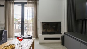 Una sala de estar moderna con chimenea, una mesa de comedor con copas de vino y un balcón con cortinas.