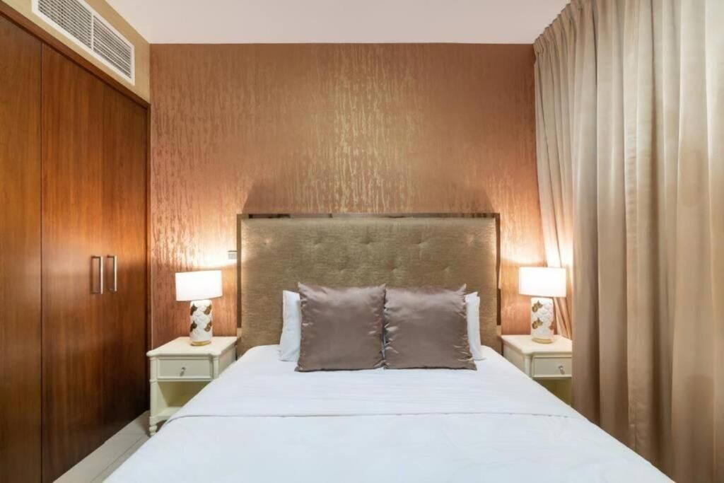 Une chambre d’hôtel avec un grand lit, une armoire en bois et deux tables de chevet avec des lampes.