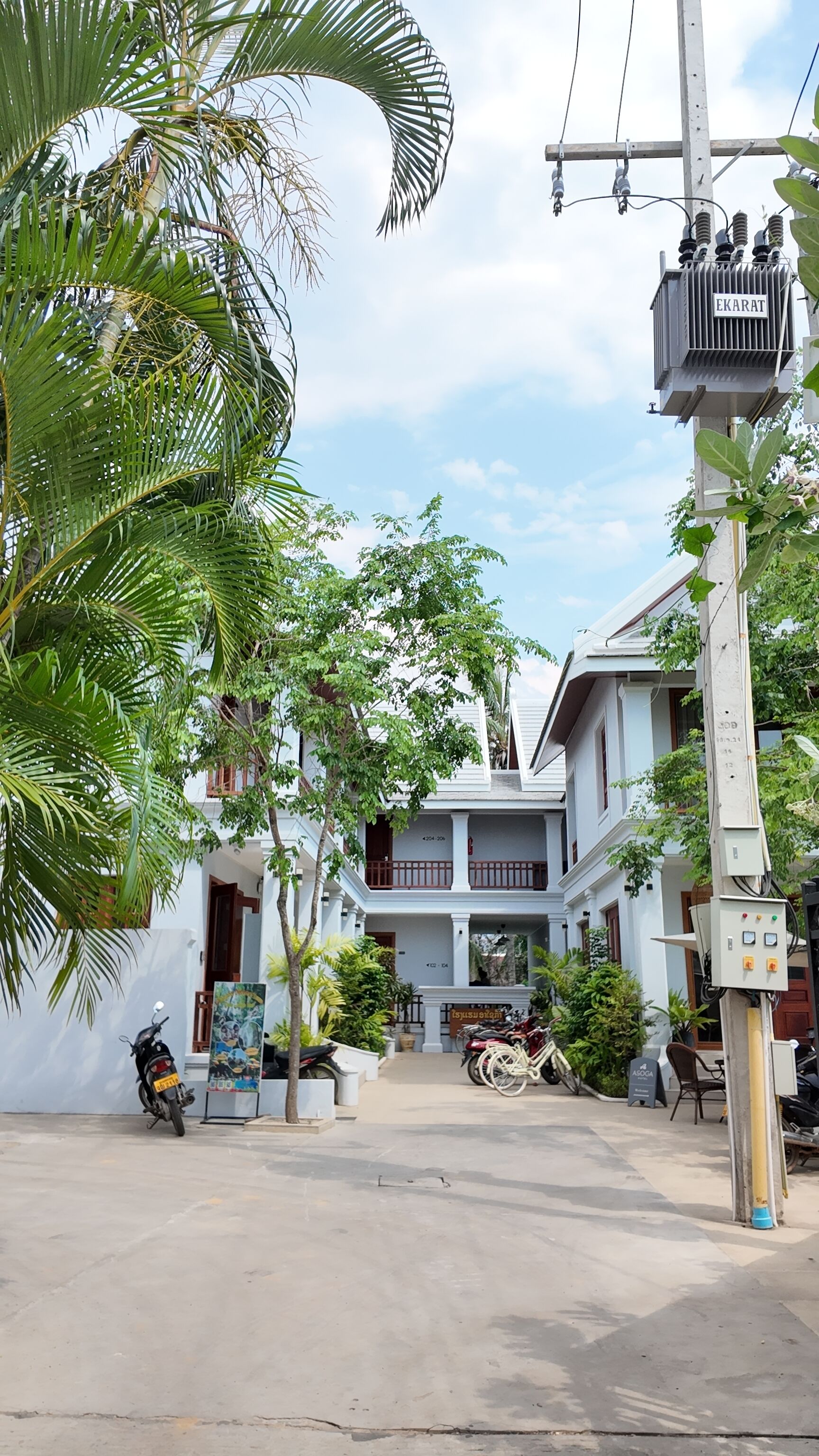 Uma área residencial com uma casa de dois andares, um poste de eletricidade e uma motocicleta estacionada.