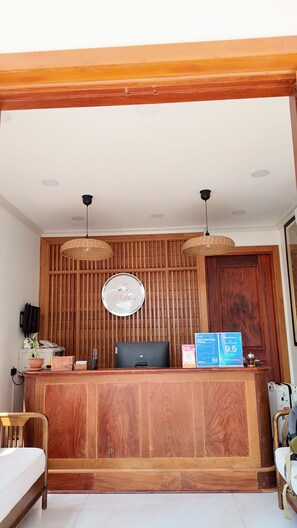 A reception desk with a wooden backdrop, a round sign, and two hanging lamps.