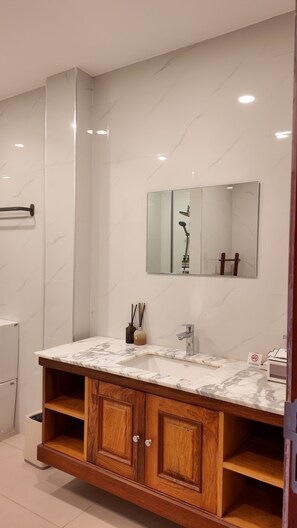 A bathroom with a marble vanity, wooden cabinets, a mirror, and a 'No Smoking' sign.