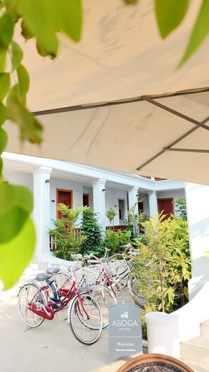 A hotel entrance with a sign, bicycles, and potted plants.