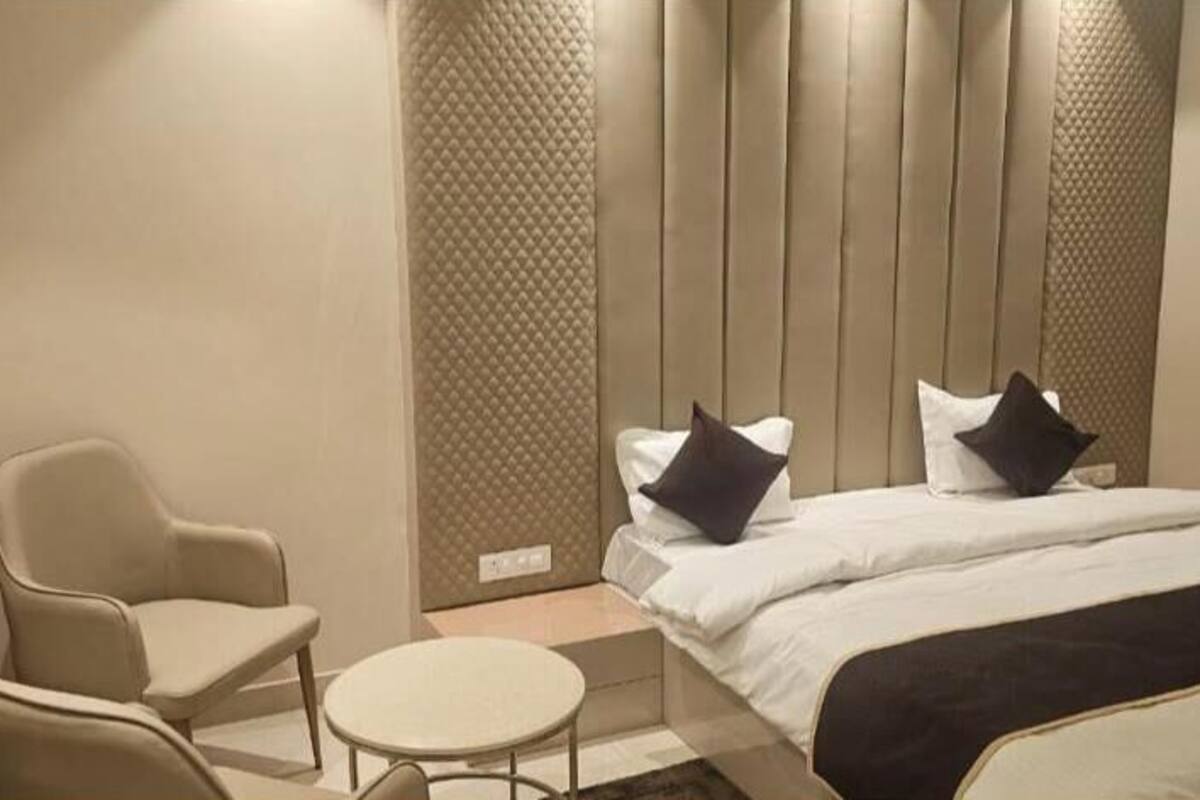 A hotel room with a bed, two chairs, a small table, and a curtain.