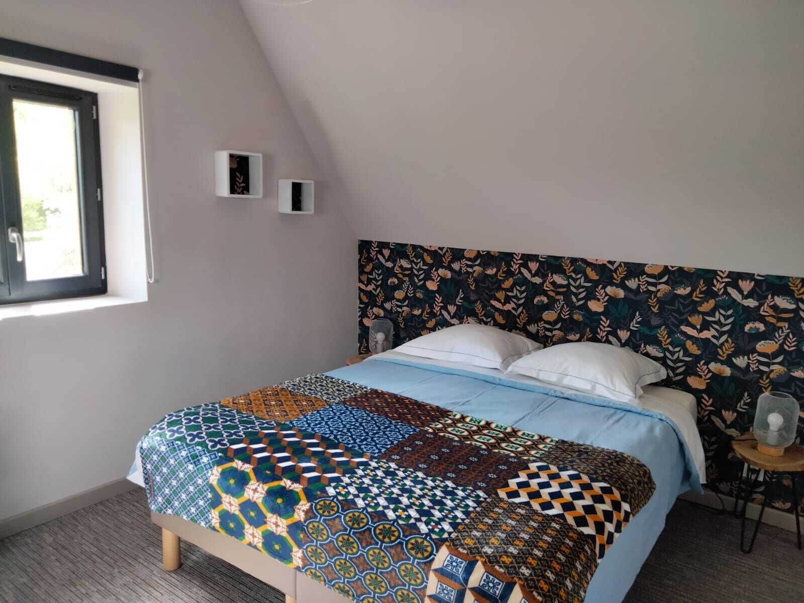 A bedroom with a bed, a window, and a wall-mounted shelf.