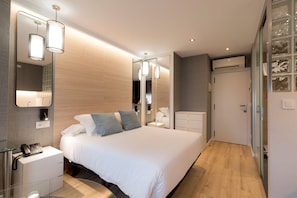 Une chambre moderne avec un grand lit, des tables de chevet, un miroir et une armoire.