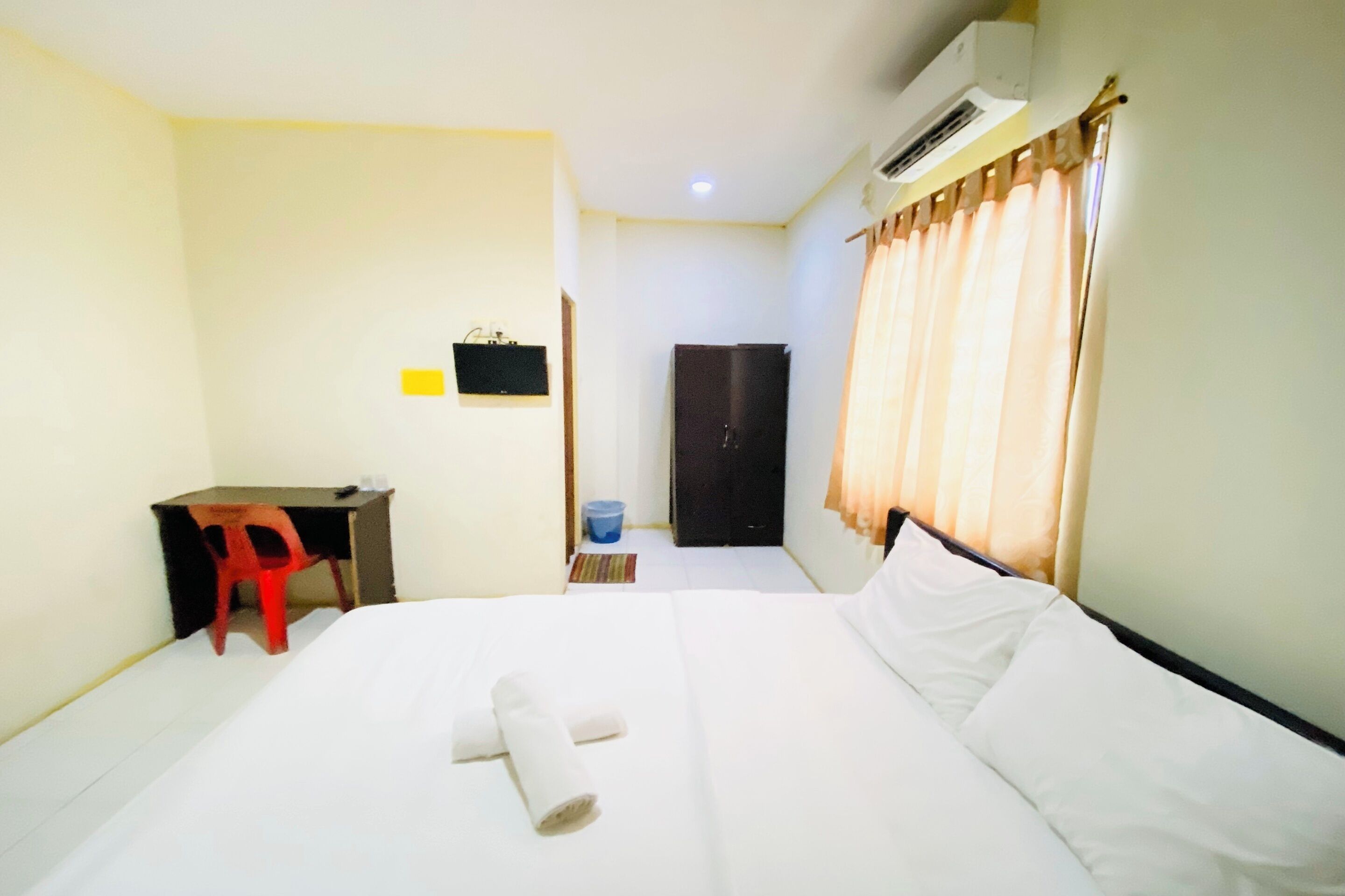 A hotel room with a bed, a desk, a chair, a wardrobe, and a bathroom.