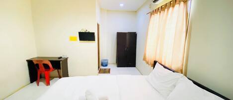 A hotel room with a bed, a desk, a chair, a wardrobe, and a bathroom.