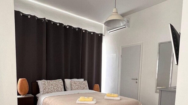 A modern bedroom with a bed, bedside tables, a desk, and a mirror.