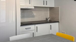 A modern kitchen with white cabinets, a grey countertop, and a dining table with chairs.