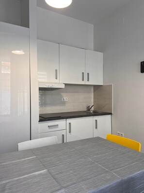 Une cuisine moderne avec des meubles blancs, un plan de travail gris et une table à manger avec des chaises.
