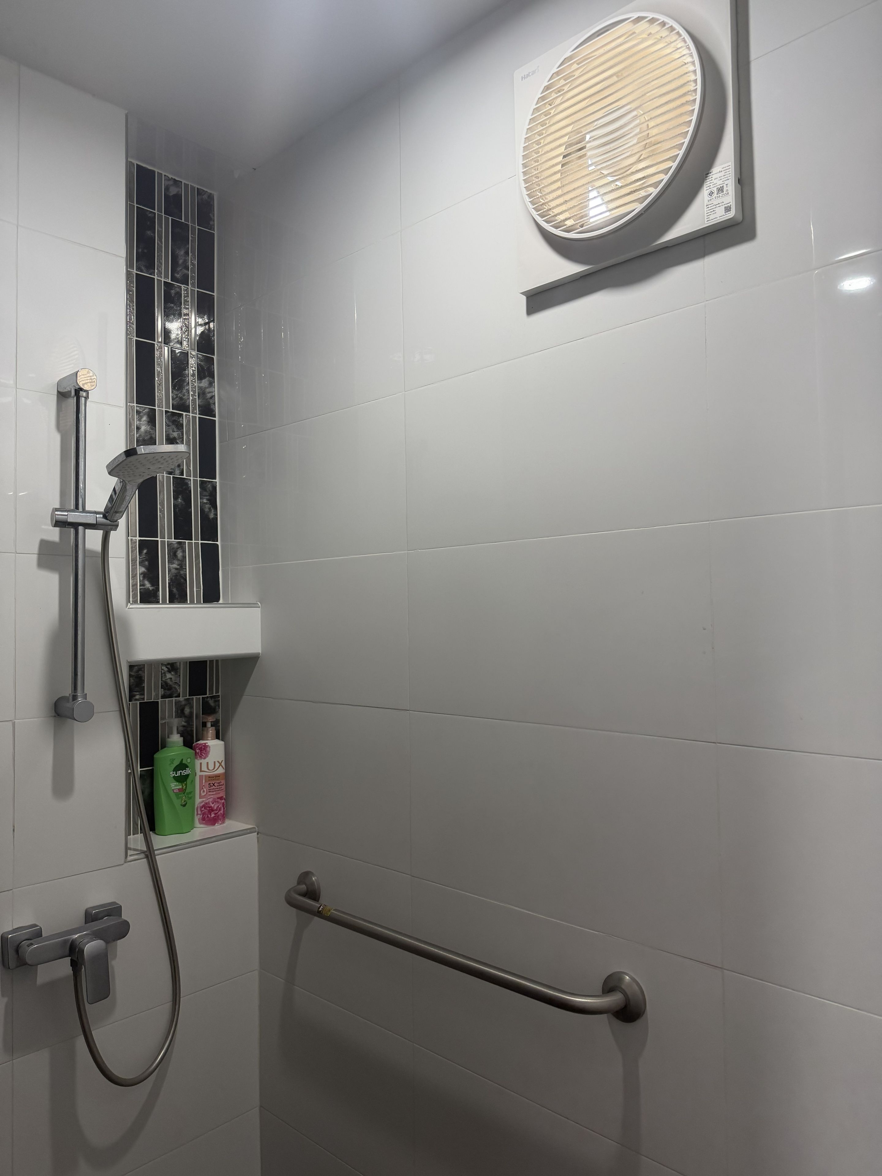 Um banheiro moderno com chuveiro, secador de mãos e porta-toalhas.
