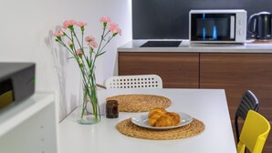 A white table with a plate of croissants, a glass vase with pink flowers, and a woven placemat. - Apartament w Śródmieściu Odnowa (Wroclaw)