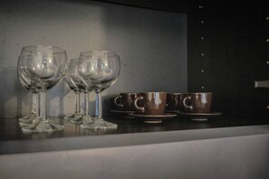 Una encimera de cocina con dos copas de vino y dos tazas de café.