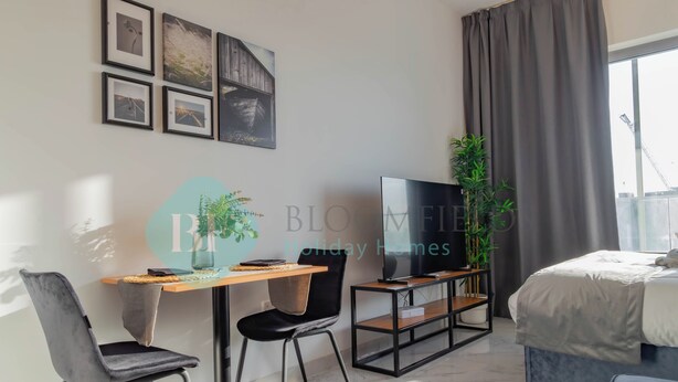 Une chambre d’hôtel moderne, équipée d’un lit, d’une télévision, d’un bureau avec une chaise et de tableaux encadrés au mur.