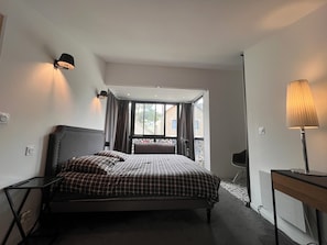 Una camera da letto con un letto, una scrivania, una lampada e vista all'esterno.