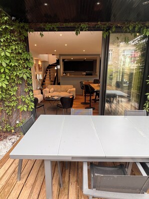 Un'area pranzo moderna con tavolo e sedie bianche, un divano e una scala che conduce a un piano superiore.