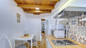 Une cuisine de taille réduite avec un plafond en bois, des murs blancs et un pare-feu en carreaux.