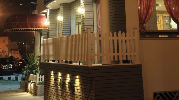Un hôtel reconnaissable à son grand panneau « HÔTEL », à une horloge et à un balcon agrémenté d’une balustrade blanche.