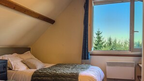 Een slaapkamer met een bed, een nachtkastje, een raam met gordijnen en een radiator.