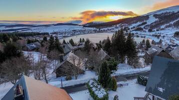 Un pueblo cubierto de nieve con casas tradicionales, un río y una puesta de sol al fondo.