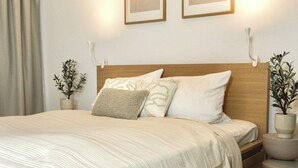A neatly made bed with a striped bedspread, a wooden headboard, and two wall-mounted picture frames. - Turmstube - 110 m² design apartment in Kürnbach, Auszeitapartments (Kürnbach)