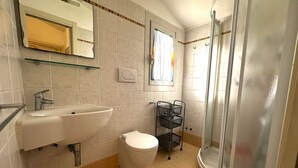 Une salle de bain équipée d’un lavabo, de toilettes et d’une douche à parois en verre.