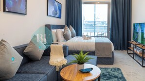 A modern hotel room with a bed, sofa, and a TV. - Bloomfields Spectacular STU in Oasis (Abu Dhabi)