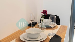 A dining table set with white plates, bowls, and wine glasses, accompanied by a vase with flowers. - Bloomfields Spectacular STU in Oasis (Abu Dhabi)