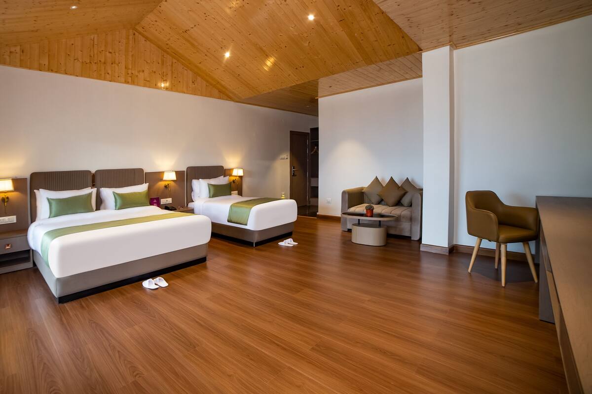 A hotel room with two beds, a sofa, a chair, and a small table.