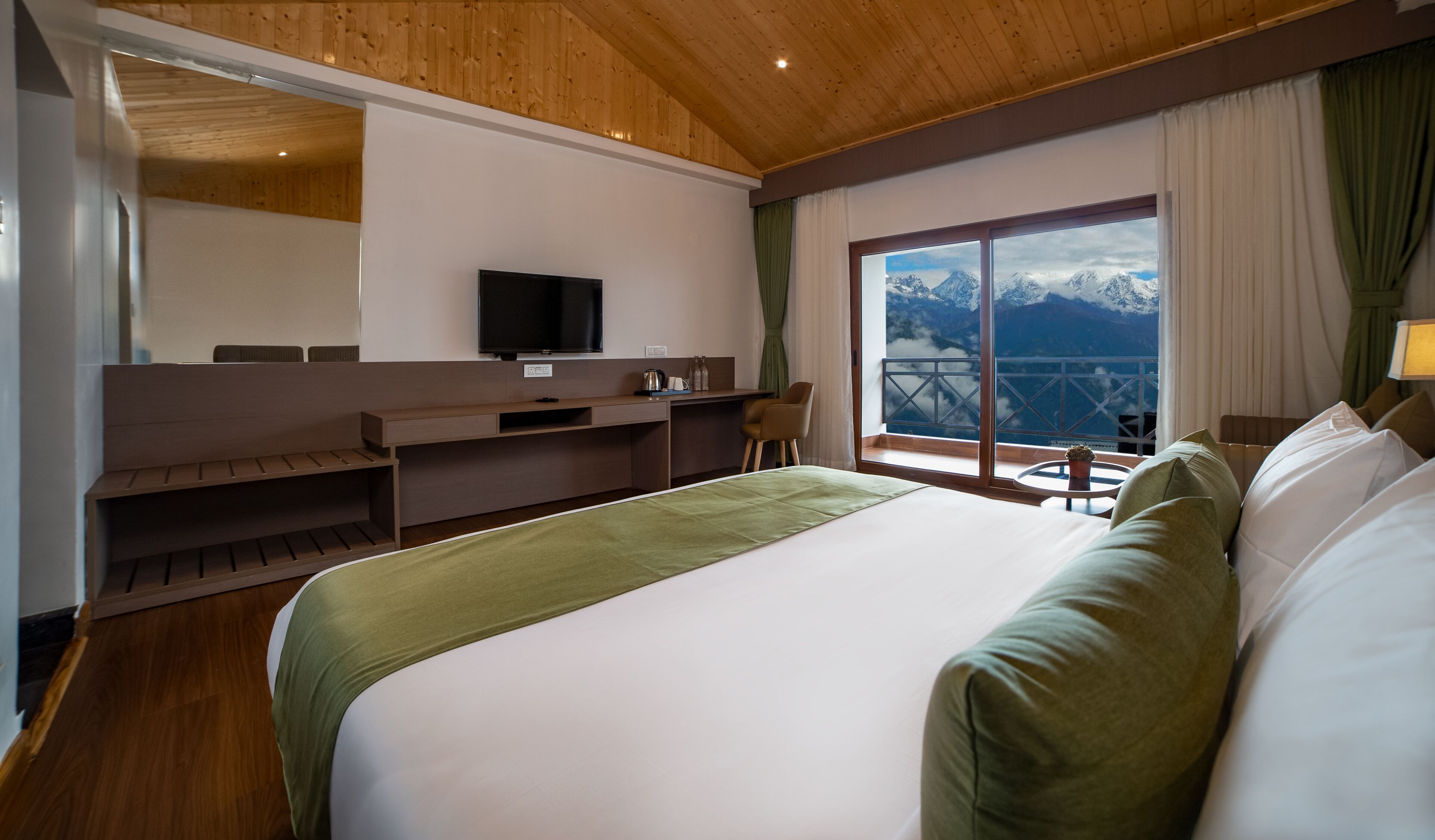 A hotel room with a bed, a desk, a chair, a television, and a window with a mountain view.