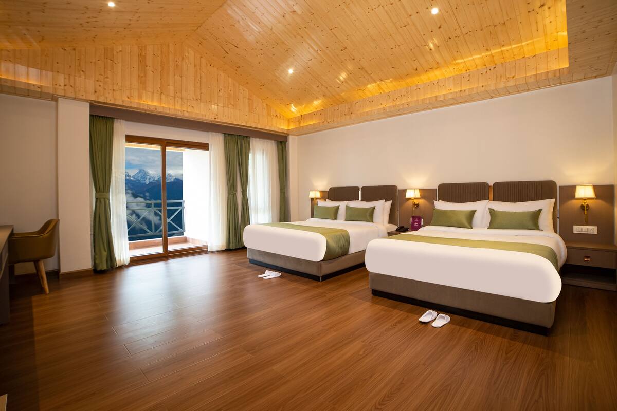 A hotel room with two beds, a desk, and a view of mountains.