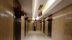 A modern hallway with elevators, polished floors, and decorative red foliage. - Breeze residence Pasay (Pasay)