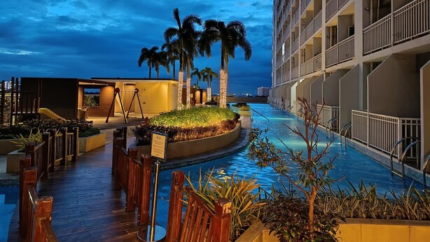A hotel pool area with a modern design, including a palm tree garden and a children's play area. - Breeze residence Pasay (Pasay)