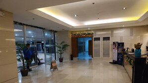 A spacious lobby with a reception desk, potted plants, and a glass entrance. - Breeze residence Pasay (Pasay)