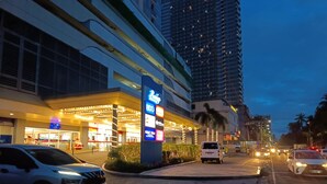 A multi-story hotel with illuminated signage and a modern facade. - Breeze residence Pasay (Pasay)