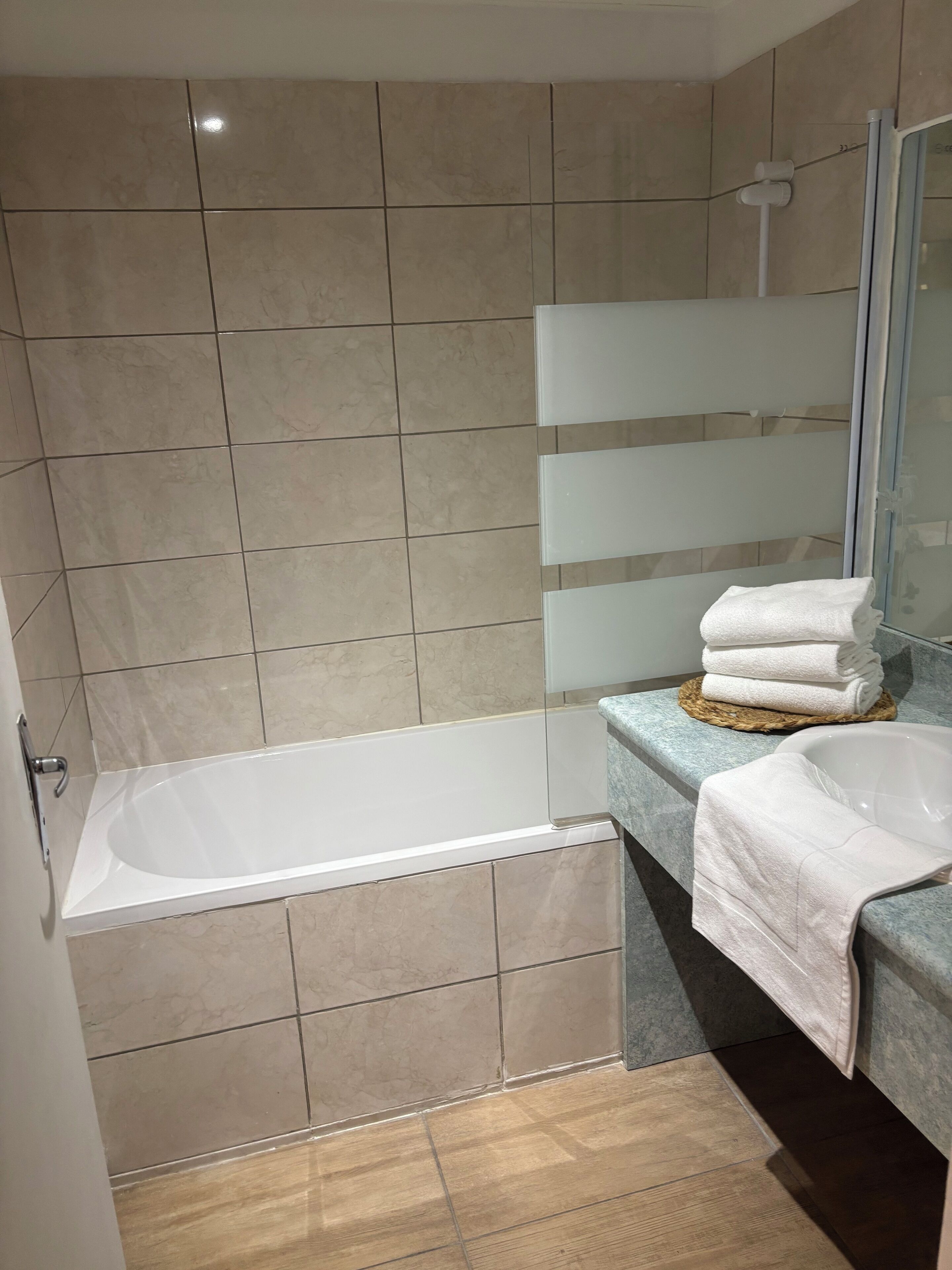 A modern bathroom with a bathtub, a sink, and a glass shower enclosure.